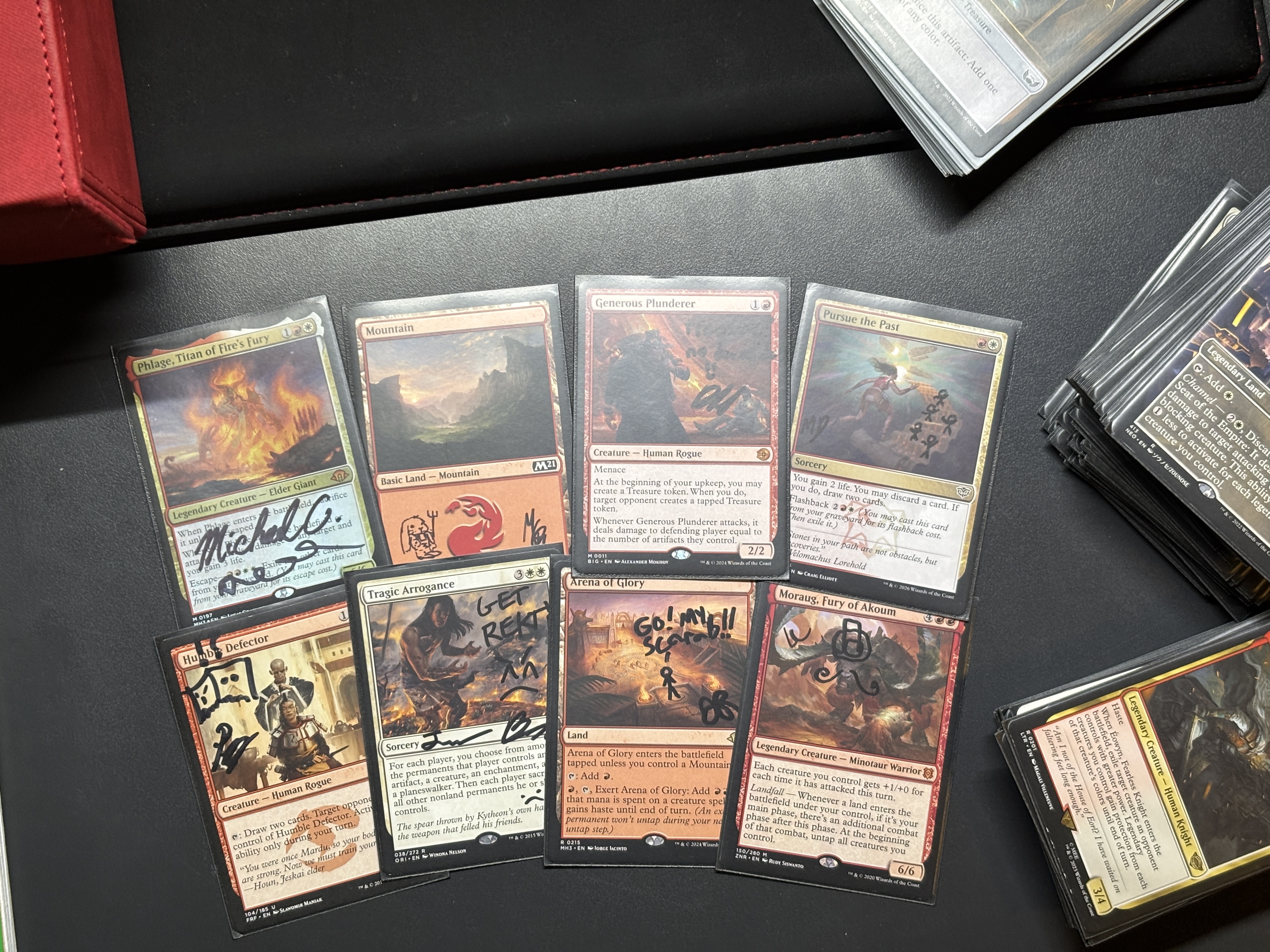 Photo of my physical copy of the Phlage commander deck, with 8 of the cards in the deck face up on a table. The cards have various signatures and doodles drawn on them.